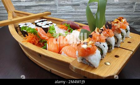 Eine Nahaufnahme von leckerem Sushi, serviert auf einer hölzernen, bootförmigen Platte in einem japanischen Restaurant Stockfoto