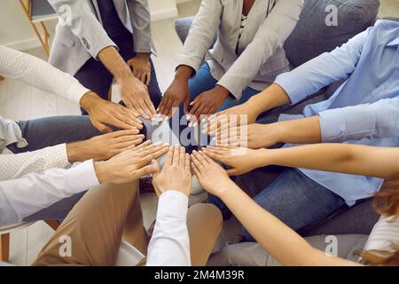 Verschiedene multirassische Männer und Frauen bilden einen Kreis, in dem ihre Hände ihre Einheit und Gleichheit zeigen. Stockfoto