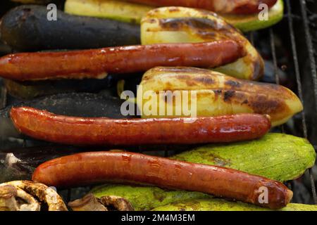 Gebratene Zucchini mit Paprika und Pilzen und Würstchen auf dem Grill im Sommer bei einem Picknick im Park, Gemüse und gegrillte Würstchen Stockfoto