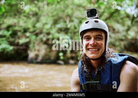 Das war so eine Erfahrung. Porträt eines fröhlichen jungen Mannes mit Schutzkleidung und Schwimmweste, während er draußen am Fluss steht Stockfoto
