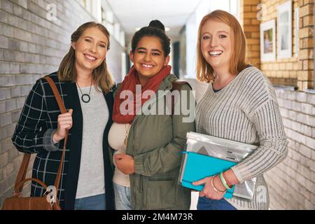 Die IT-Clique auf dem Campus. Porträt von drei attraktiven jungen Universitätsstudenten, die in einem Campusflur stehen. Stockfoto