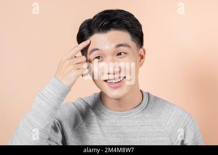 Ein Mann, der mit einem Pickel auf die Stirn zeigt Stockfoto