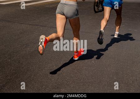 Frauen und Männer Rennen auf dunklem Asphalt Stockfoto