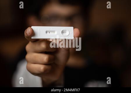 Mann, der das Rapid Antigen Test-Kit mit negativem Ergebnis während des COVID-19-Tests hält. Coronavirus Selbstnasal- oder Heimtest, Lockdown und Heimisolierung Stockfoto