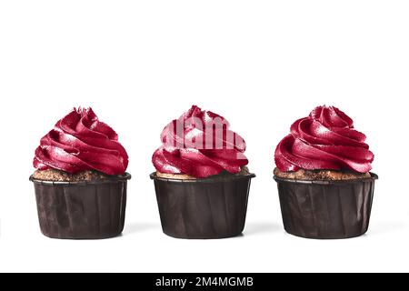 Drei köstliche Schokoladen-Cupcakes mit Glasur auf isoliertem weißem Hintergrund. In trendigen magentafarbenen Farben des Jahres 2023. Modell für Ihre Konstruktion. Nahaufnahme. Platz für Text. Stockfoto