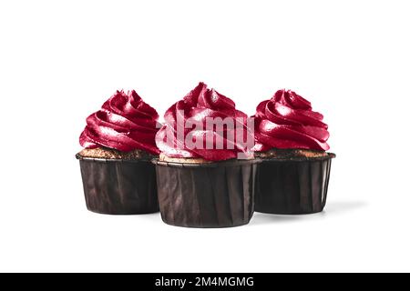 Drei köstliche Schokoladen-Cupcakes mit Glasur auf isoliertem weißem Hintergrund. In trendigen magentafarbenen Farben des Jahres 2023. Modell für Ihre Konstruktion. Nahaufnahme. Platz für Text. Stockfoto