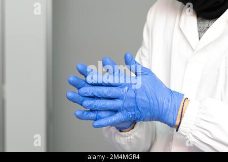 Nahaufnahme weiblicher Hände in blauen Operationshandschuhen Desinfektionsmittel reiben. Sicherheitsumfeld und Vorsichtsmaßnahmen während der Coronaviruspandemie im Krankenhaus Konzept Stockfoto