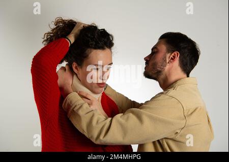 Eine Frau, die eine Halskrause trägt, unterstützt von einem Mann auf einem weißen und grauen Hintergrund isoliert Stockfoto