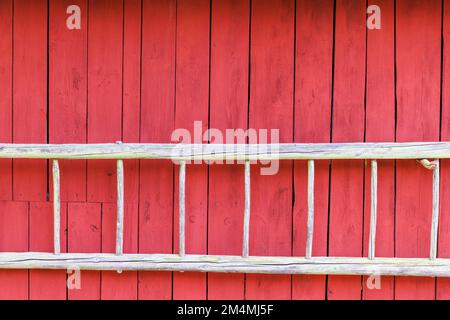 Alte Holzleiter auf einer roten Holzwand Stockfoto