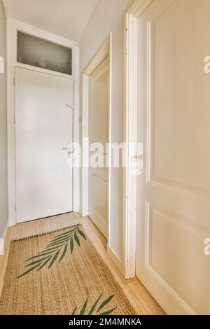 Ein leeres Zimmer mit Holzfußboden und weißen Türen auf beiden Seiten, es gibt eine Tür in der Ecke, die zu einem anderen Zimmer führt