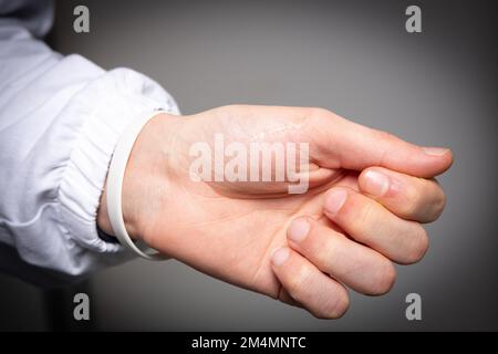 Nahaufnahme einer Hand und eines Handgelenks eines weissen Mannes isoliert auf grauem Hintergrund. Begriff des Karpaltunnels und Gelenkschmerzes bei Sehnenentzündung Stockfoto