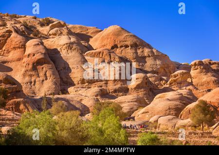 Petra, Jordanien - 3. November 2022: Touristen, die einen Spaziergang entlang des Sandsteinschluchten, Felsformationen, die zum UNESCO-Weltkulturerbe gehören Stockfoto