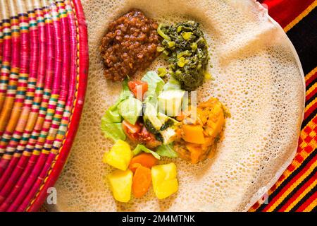 Teller mit Injera-Brot mit verschiedenen Themen wie Fleisch, Salat und Gemüse. Injera ist ein traditionelles Brot in Äthiopien. Stockfoto