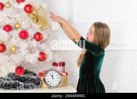 Lieblingstag des Jahres. Weihnachtsfeier. Freuen Sie sich unglaublich auf weihnachten. Ein kleines Mädchen, der weihnachtsbaum wartet auf die Uhr. Kindheit Stockfoto