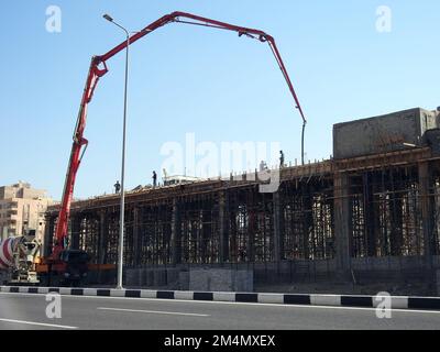 Kairo, Ägypten, November 30 2022: Eine Lkw-montierte Betonauslegerpumpe am Straßenrand, die Beton in ein neues Gebäude gießt, selektiver Fokus von Concre Stockfoto