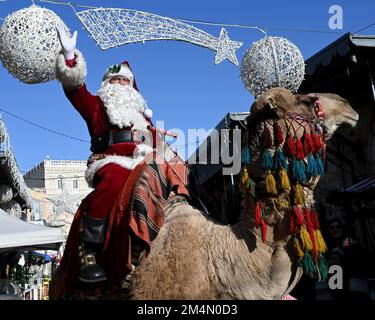 Jerusalem, Israel. 22. Dezember 2022. ISSA Kassissieh, verkleidet als Weihnachtsmann, winkt von einem Kamel in der Altstadt von Jerusalem, am Donnerstag, den 22. Dezember 2022, Tage vor Weihnachten. Foto von Debbie Hill/ Kredit: UPI/Alamy Live News Stockfoto