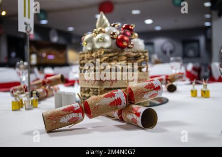 Cracker auf einem dekorierten Tisch im Veranstaltungsraum, der während der Weihnachtsfeier in Großbritannien eingerichtet ist Stockfoto