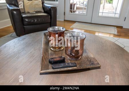 Ein Paar passende Kerzen, die auf einem Tablett mit Fernbedienung auf einem Couchtisch als Wohnzimmerdekoration sitzen Stockfoto