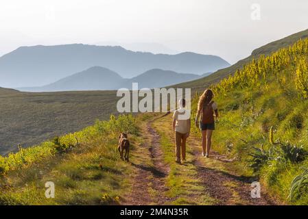 Glückliche Familie mit Kind und Hundewanderung in den Bergen Stockfoto