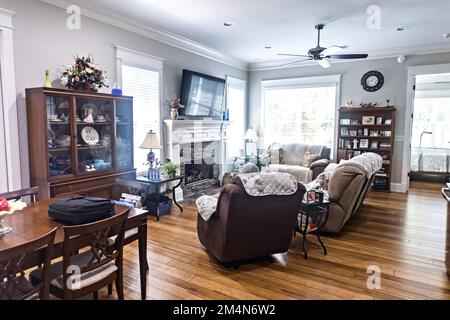 Ein traditionelles Wohnzimmer mit Kamin, Hartholzböden und komfortablem Zweisitzer-Sofa und Sessel Stockfoto