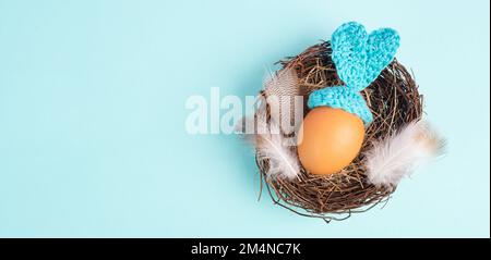 Osterhasen oder Kaninchen in einem Vogelnest, aus einem Ei und Häkelohren, Frühlingsferien, Grußkarte Stockfoto