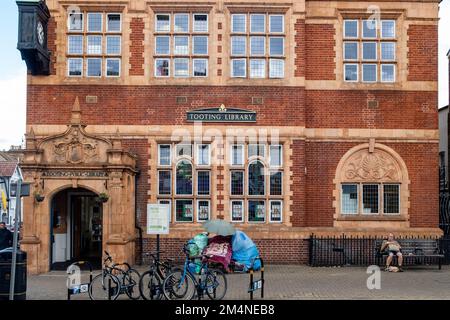 London - September 2022: Tooting Library auf der Mitcham Road mit Obdachloser, die seit vielen Jahren auf der Bank draußen lebt Stockfoto