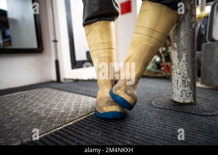 Fischer in gummistiefeln, wasserfester Kleidung und Handschuhen auf einem Fischerboot in australien Stockfoto