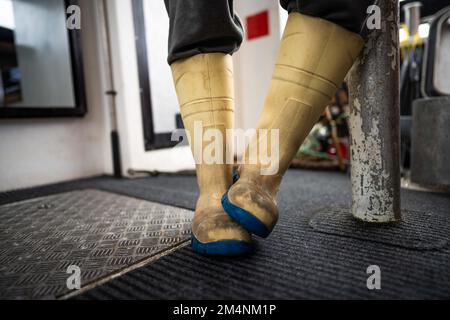 Fischer in gummistiefeln, wasserfester Kleidung und Handschuhen auf einem Fischerboot in australien Stockfoto