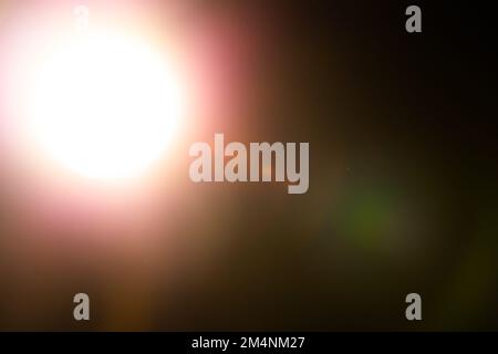 Warme Lichtreflexionen überlagern sich auf schwarzem Hintergrund. Sphärisches optisches Leck. Stockfoto