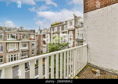 Ein Balkon mit weißen Geländern und Backsteingebäuden im Hintergrund, an einem hellen sonnigen Tag - Stockfoto Stockfoto