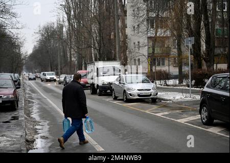 Kiew, Ukraine. 22. Dezember 2022. Ein Mann trägt Plastikflaschen während eines Stromausfalls in Kiew. Die russische Armee führte massive Raketen- und Kamikaze-Drohnenangriffe auf die ukrainische Energieinfrastruktur durch. Nach schweren Schäden am Stromnetz in vielen Städten der Ukraine führte die National Power Company Ukrenergo Notfall- und stündliche Stromausfälle ein. (Kreditbild: © Sergei Chuzavkov/SOPA Images via ZUMA Press Wire) Stockfoto