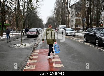 Kiew, Ukraine. 22. Dezember 2022. Ein Mann trägt eine Plastikflasche während eines Stromausfalls in Kiew. Die russische Armee führte massive Raketen- und Kamikaze-Drohnenangriffe auf die ukrainische Energieinfrastruktur durch. Nach schweren Schäden am Stromnetz in vielen Städten der Ukraine führte die National Power Company Ukrenergo Notfall- und stündliche Stromausfälle ein. (Kreditbild: © Sergei Chuzavkov/SOPA Images via ZUMA Press Wire) Stockfoto