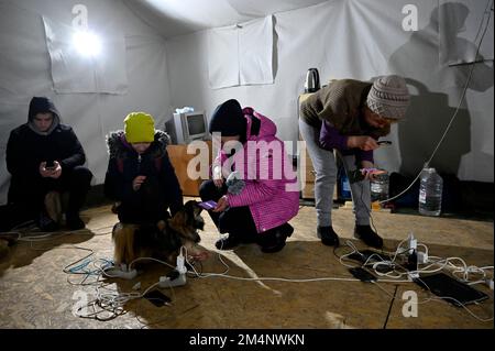 Kiew, Ukraine. 22. Dezember 2022. Während eines Stromausfalls in Kiew laden die Leute ihre Handys auf der mobilen Polizeistation auf. Die russische Armee führte massive Raketen- und Kamikaze-Drohnenangriffe auf die ukrainische Energieinfrastruktur durch. Nach schweren Schäden am Stromnetz in vielen Städten der Ukraine führte die National Power Company Ukrenergo Notfall- und stündliche Stromausfälle ein. (Kreditbild: © Sergei Chuzavkov/SOPA Images via ZUMA Press Wire) Stockfoto