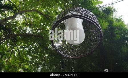 Lampenlampe aus gewebtem Bambusbezug, die im öffentlichen Park im Baum hängt Stockfoto