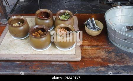 Gewürze aus Chilisauce, Tofu, Kartoffel, Gurke, Bohnensprossen in traditionellem Tontopf Stockfoto