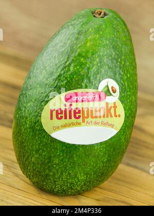 Hamburg, Deutschland - Dezember 6 2022: Avocado und Label mit Reifepunkt auf Holz - Avocado und Etikett mit Reifungspunkt auf Holz Stockfoto