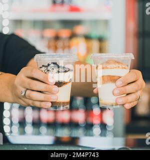 Nahaufnahme von Händen, die Desserts in Plastikbechern halten Stockfoto