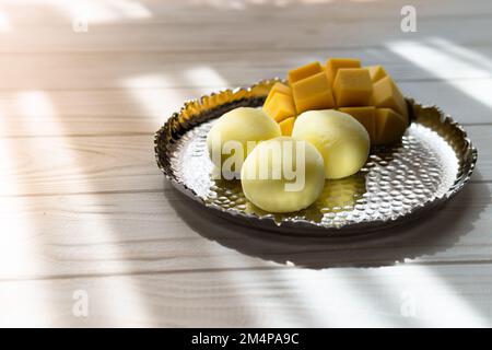 Leckeres Dessert Mochi mit Mangofrucht auf Holzhintergrund, Nahaufnahme. Traditionelles japanisches Reiskuchen-Dessert Stockfoto