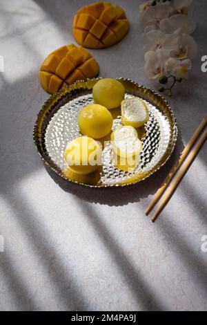 Leckeres Dessert Mochi mit Mangofrucht auf grauem Hintergrund, Nahaufnahme. Traditionelles japanisches Reiskuchen-Dessert Stockfoto