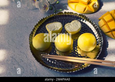 Leckeres Dessert Mochi mit Mangofrucht auf grauem Hintergrund, Nahaufnahme. Traditionelles japanisches Reiskuchen-Dessert Stockfoto