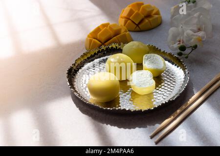 Leckeres Dessert Mochi mit Mangofrucht auf grauem Hintergrund, Nahaufnahme. Traditionelles japanisches Reiskuchen-Dessert Stockfoto