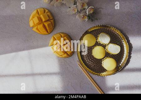 Leckeres Dessert Mochi mit Mangofrucht auf grauem Hintergrund, Nahaufnahme. Traditionelles japanisches Reiskuchen-Dessert Stockfoto