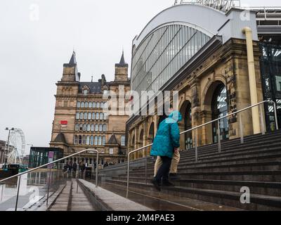 Ein Mann und eine Frau gehen im Dezember 2022 die nasse Treppe unter einem regnerischen Himmel in Richtung Bahnhof Liverpool Lime Street hinauf. Stockfoto