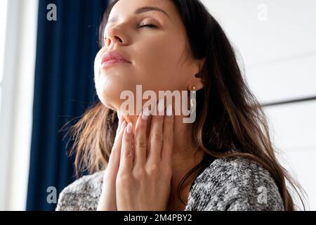 Junge Frau Selbstuntersuchung Schilddrüse. Hashimoto oder Schilddrüsenkrebs Konzept Stockfoto