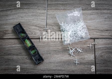 Wasserwaage und Kunststoffkreuze auf Fliesen. Fliesen funktionieren. Stockfoto