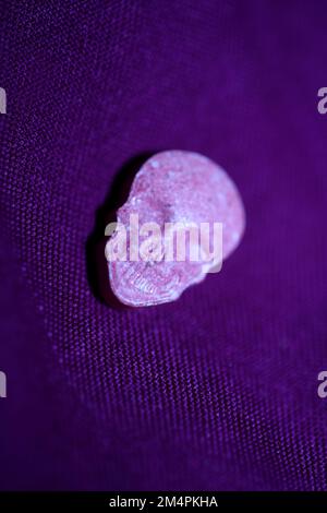 Rosa Schädel Ecstasy-Pille Nahaufnahme Hintergrund qualitativ hochwertige Drucke Purple Army-Drogen Substanz hochdosierte psychedelische Lebensweise Stockfoto
