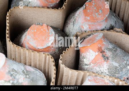 Alte, gebrauchte und verwitterte Töpfe aus Lehm werden durch eine Zwischenschicht aus Pappe voneinander getrennt. Stockfoto