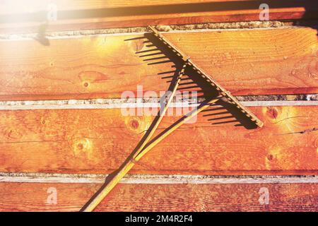 Holzrechen hängt an der Wand eines Holzhauses. Altes Bauernwerkzeug. Hochwertiges Foto Stockfoto