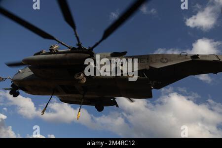 EIN US-AMERIKANISCHER Marine CH-53E Super Hallion mit Marine Medium Tiltrotor Squadron 262 (verstärkt), 31. Marine Expeditionary Unit, senkt seine Haken, um die Fracht während einer Helikopter-Team-Übung in Camp Hansen, Okinawa, am 20. Dezember 2022 anzuheben. Bei der HST-Übung handelte es sich um einen Test, der durchgeführt wurde, um Piloten im Umgang mit Anschlagmitteln zu zertifizieren und die Flugfertigkeiten beim Heben von Fracht zu verbessern. Die MEU von 31., die einzige fortlaufend nach vorn verlegte MEU des Marine Corps, bietet eine flexible und tödliche Truppe, die bereit ist, als führende Krisenreaktionstruppe im Indo-Pazifik-Raum ein breites Spektrum militärischer Operationen durchzuführen. Stockfoto