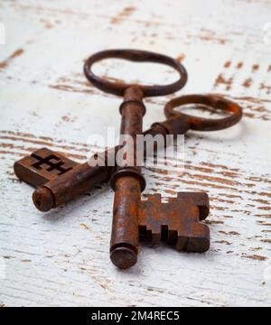 Rosted Skeleton Keys Zusammen Auf Weißem, Verwittertem Holztisch Still Life Stockfoto